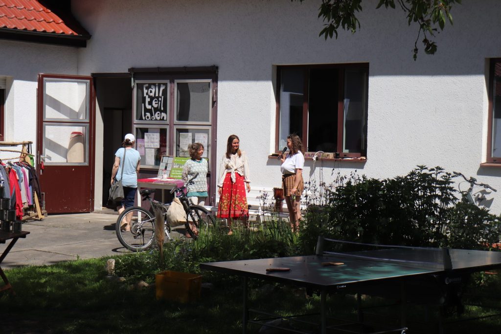 Der Fair-Teil-Laden von außen mit Kleiderständern und Fahrrädern